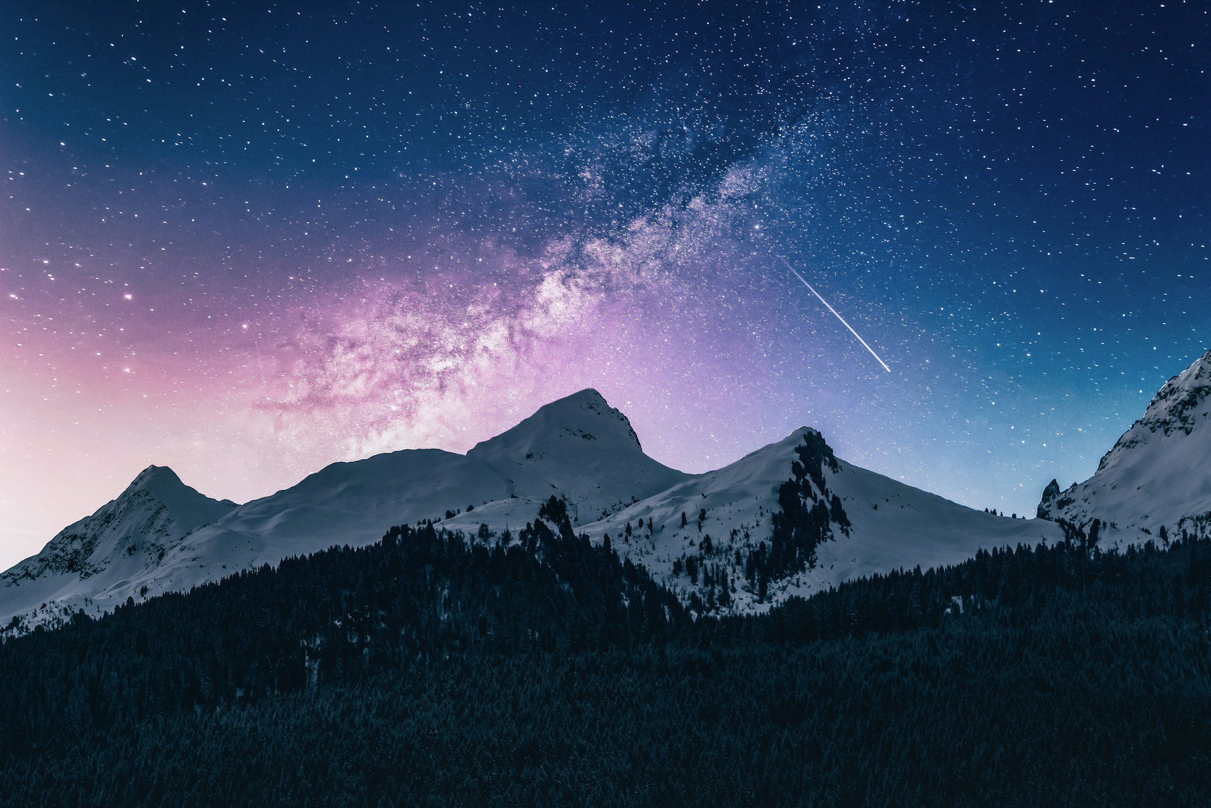 A star-filled sky above snowy mountain peaks